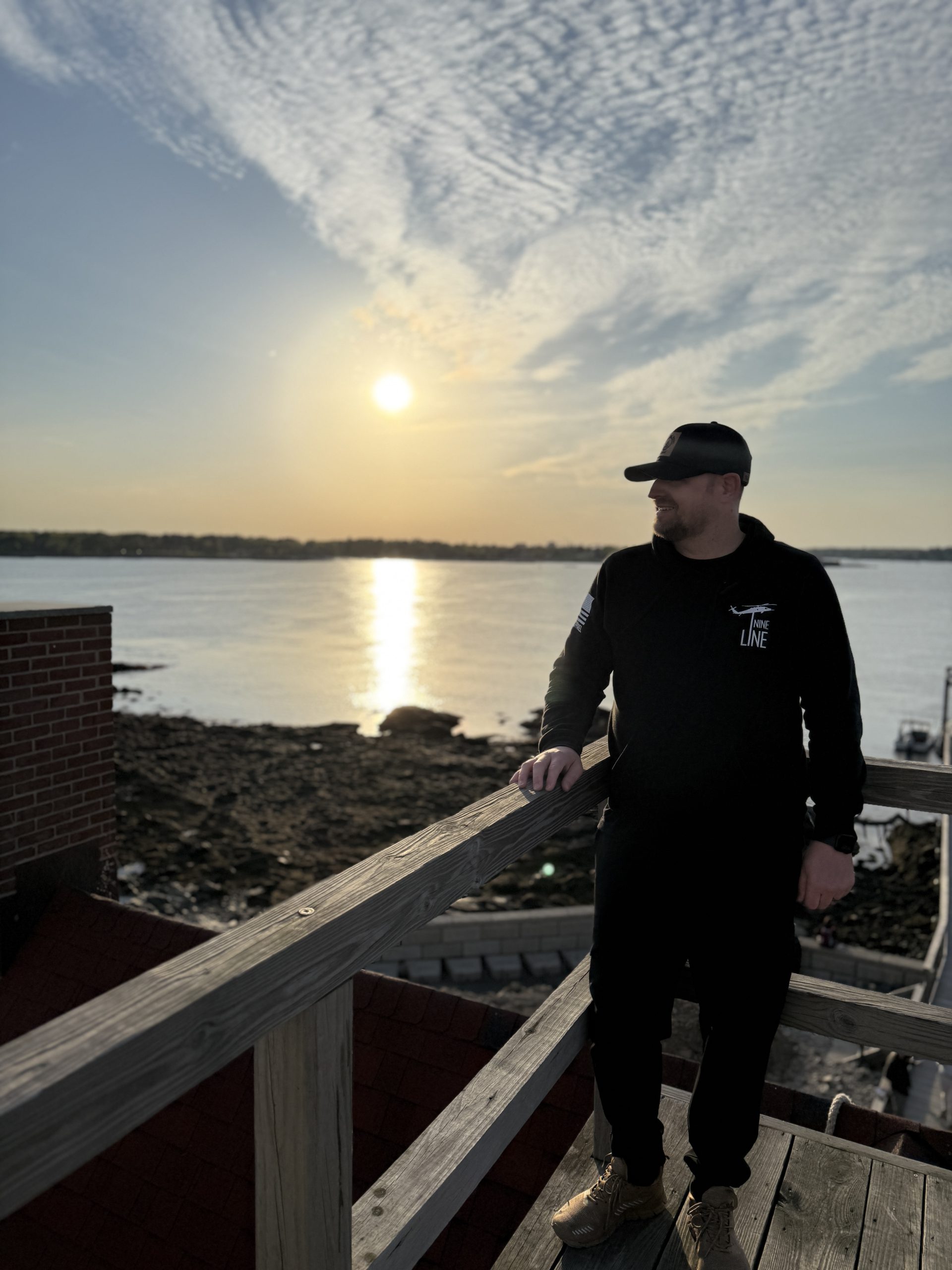 Male wearing a hat standing with the sun setting behind him
